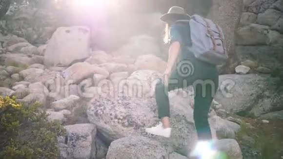 年轻漂亮的当地女孩带着背包和相机独自徒步旅行在约塞米蒂森林缓慢的运动中攀爬大石头视频的预览图
