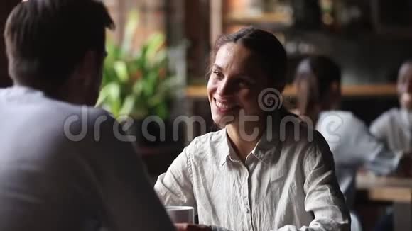微笑的年轻女子在咖啡厅与男人交谈视频的预览图