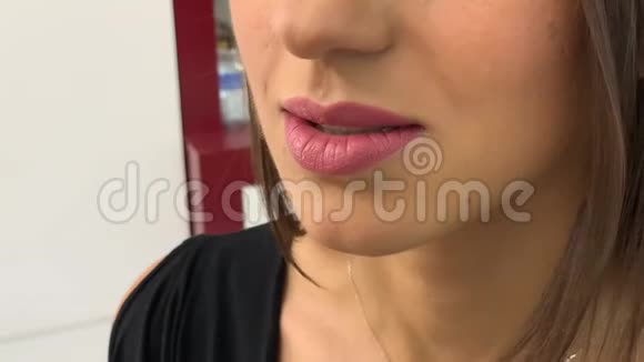 化妆师专业地将口红涂在模特漂亮的嘴唇上视频的预览图