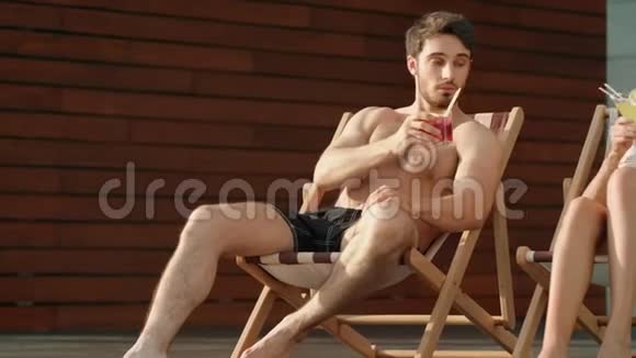 夏日情侣在太阳椅上喝鸡尾酒性感的女人穿比基尼放松视频的预览图