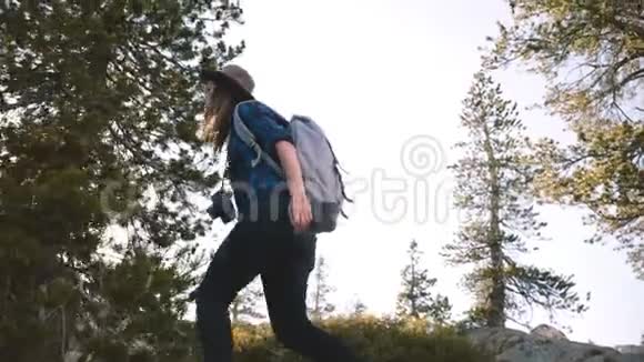 年轻美丽的旅游女孩带着背包和相机独自在约塞米蒂国家公园慢动作大石头上徒步旅行视频的预览图