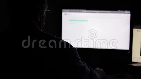戴眼镜的年轻人晚上在微光下用电脑工作视频的预览图