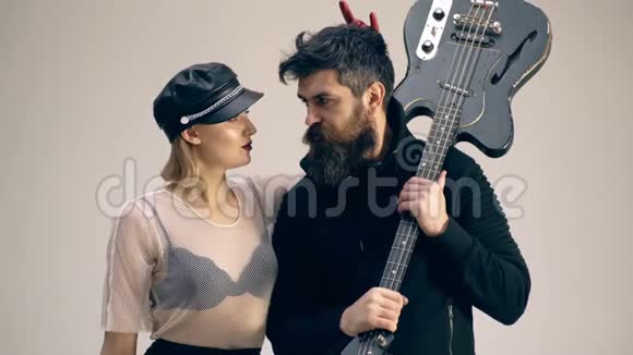 有胡子的男人拿着吉他一个女人戴着皮帽子互相看着对方有吉他的硬摇滚情侣妇女视频的预览图