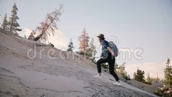 年轻漂亮的女游客独自背着背包徒步旅行在约塞米蒂国家公园缓慢地攀爬一块巨大的岩石视频的预览图