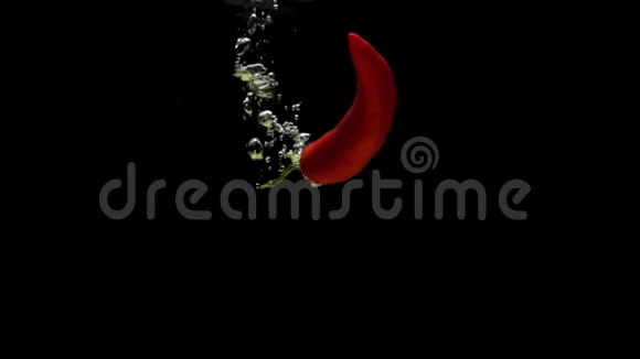 一只红辣椒在黑色背景下落入透明水视频的预览图