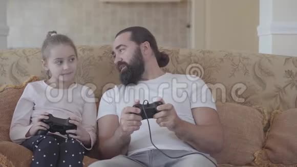 小女儿和她有趣的父亲在电视上玩电子游戏在舒适的客厅里有很大的情感父亲和视频的预览图