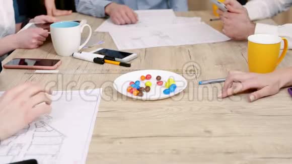 对雇员的培训上班族从桌旁的盘子里拿糖果双手特写团队建设理念视频的预览图