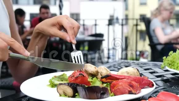 女人用刀切烤番茄女孩用叉子吃蔬菜烤架视频的预览图