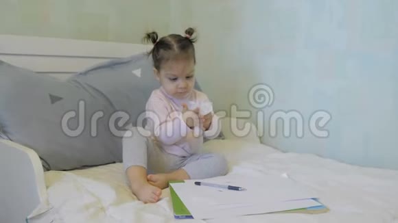 一个可爱的女婴在床上用餐巾擦手视频的预览图
