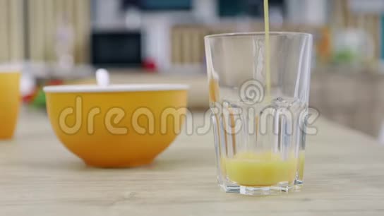 女人把黄色的水果饮料从瓶子里倒入玻璃杯里视频的预览图