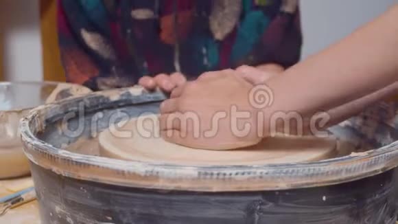 女性的手在旋转的陶工车轮上视频的预览图
