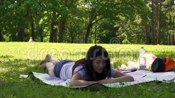 白天年轻的亚洲女孩躺在公园的空地上视频的预览图