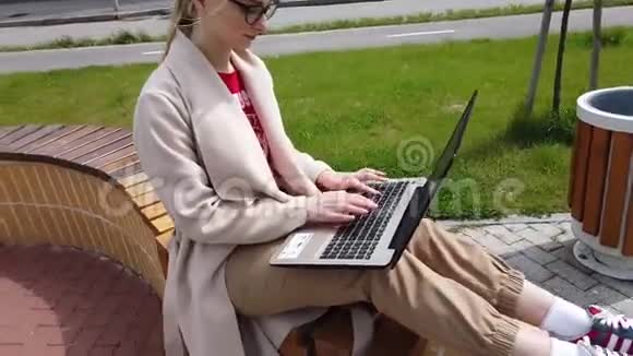 坐在长凳上用笔记本电脑工作的女孩视频的预览图