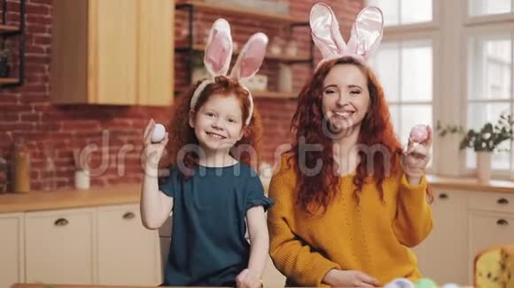 有趣的肖像快乐的母亲和她的小女儿玩复活节彩蛋快乐的家庭长着兔子耳朵视频的预览图