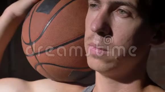 严肃的篮球运动员肩上抱着球侧着头看视频的预览图