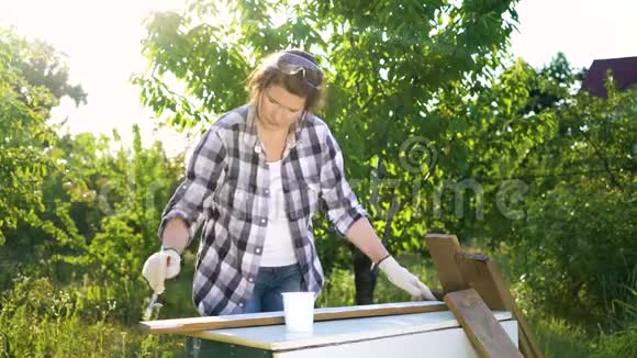 阳光洒在工艺品上女人在后院用白色油漆画木板视频的预览图