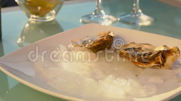 女性的手把打开的牡蛎放在一个装有冰块的盘子里视频的预览图
