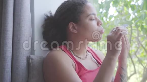 美国黑人妇女坐在窗台上用指甲锉剪指甲她关心自己视频的预览图