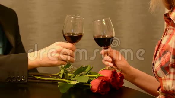 男人和女人在餐厅桌上端着一杯红玫瑰花的红酒视频的预览图