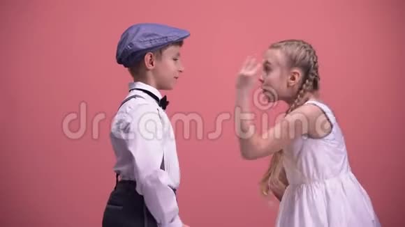 两个年幼的孩子在粉红色背景下进行情感上的手势和争论视频的预览图