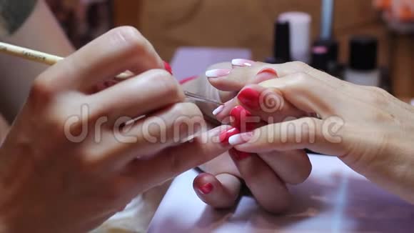 美甲师用胶水涂抹指甲并用一种特殊的工具涂上莱茵石视频的预览图