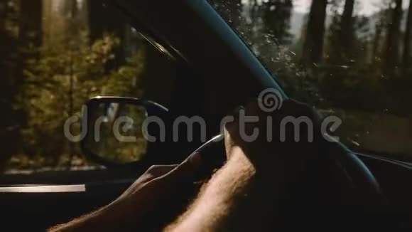美丽的特写镜头两只雄手握着汽车方向盘沿着森林道路行驶在约塞米蒂缓慢的运动视频的预览图