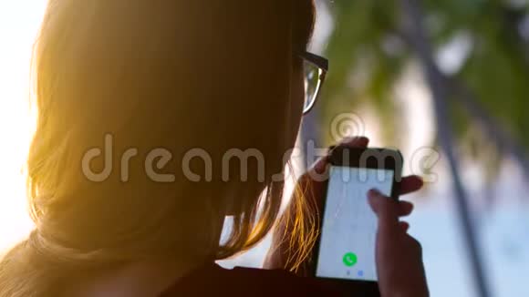 戴眼镜的后侧女士在智能手机上拨号码视频的预览图