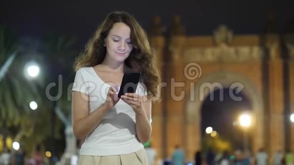 使用手机站在巴塞罗那皇家剧院的旅游女孩视频的预览图