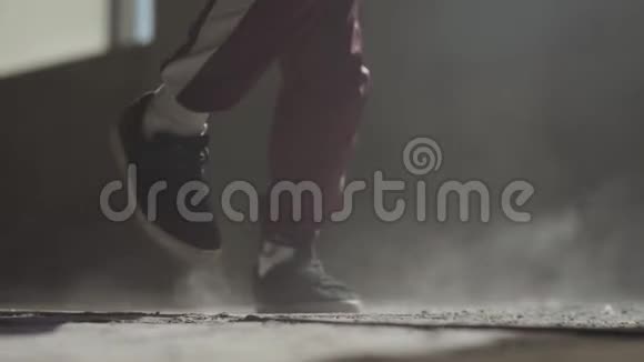 一个穿着运动鞋的练习舞者的脚在废弃的房子里尘土飞扬的混凝土地板上跳舞视频的预览图