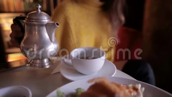 穿着黄色毛衣的年轻美女在舒适的咖啡馆里吃早餐喝茶视频的预览图