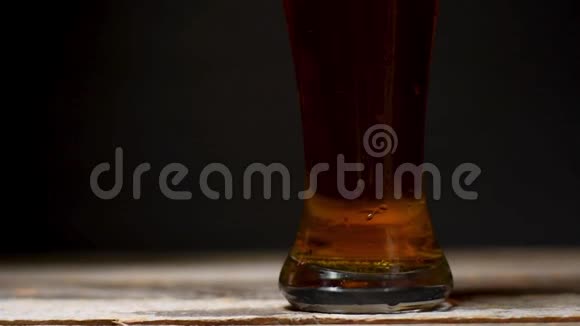 啤酒泡沫从边缘倾泻而出黑色背景的冷啤酒视频的预览图