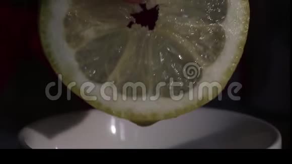 一个人把柠檬汁挤到一个杯子里柠檬新鲜多汁可见汁液滴入杯中近距离射击视频的预览图