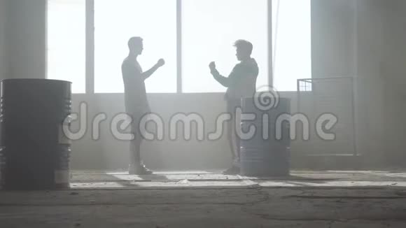 两个年轻人在废弃建筑的尘土飞扬的房间里练习跳舞朋友们玩石头剪刀视频的预览图
