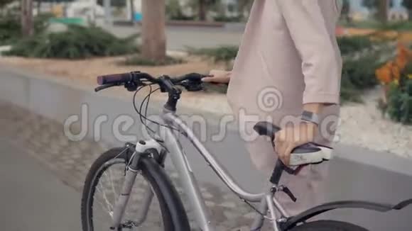 年轻的骑自行车的女性正在城市街道上滚动她的自行车手的详细视图视频的预览图
