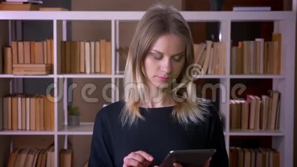 使用平板电脑为年轻有魅力的女学生拍摄特写镜头并在室内拍摄绿色屏幕视频的预览图