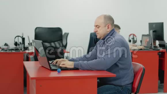 40多岁的男人在电脑前工作在办公室里揉捏疲惫的手视频的预览图