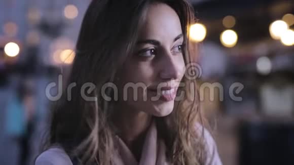 迷人的优雅女人从镜头旁看着微笑着为夜晚城市画像提供灯光视频的预览图