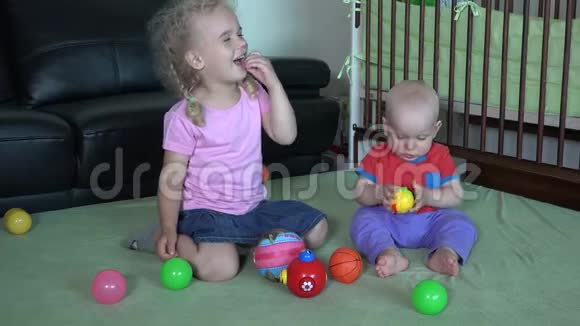 快乐的姐姐吻她弟弟在家玩五颜六色的球视频的预览图