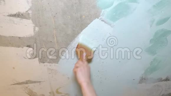 一个人在一堵破旧的灰白色墙上刷出一道浅划的蓝色油漆视频的预览图