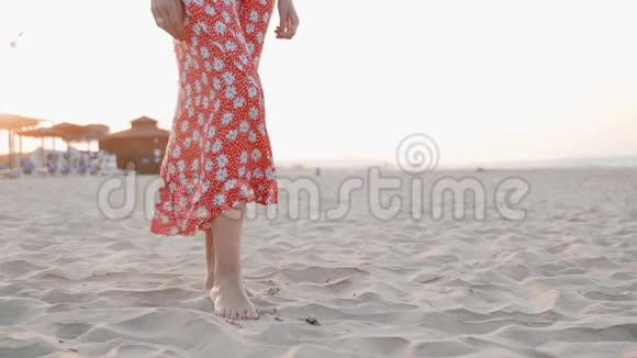 日落时分站在沙滩上的身着红色礼服的女子双腿特写镜头视频的预览图