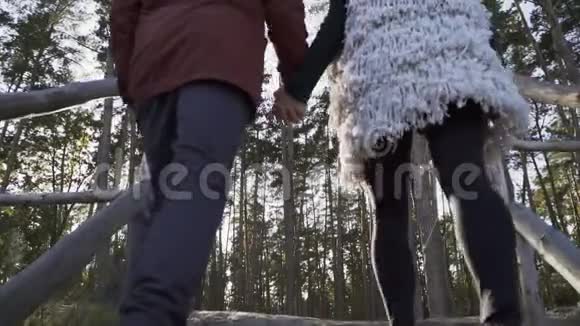 年轻人和女孩牵着手爬上木楼梯穿过森林年轻夫妇花时间视频的预览图
