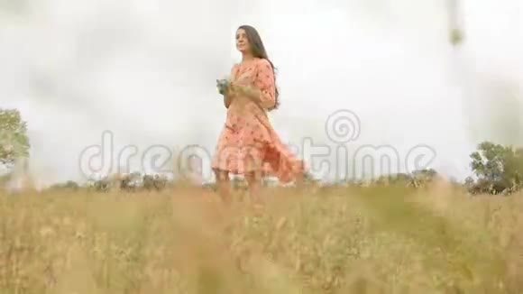 漂亮的女孩穿着一件挥动的裙子拍摄大自然慢动作手拿相机视频的预览图