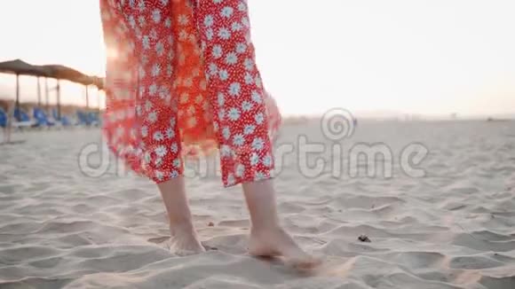 日落时分站在沙滩上的身着红色礼服的女子双腿特写镜头视频的预览图