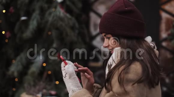漂亮的女人用红色智能手机站在街上背景圣诞装饰视频的预览图