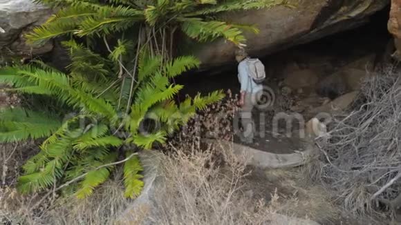 带背包攀登进入大石洞的女游客视频的预览图