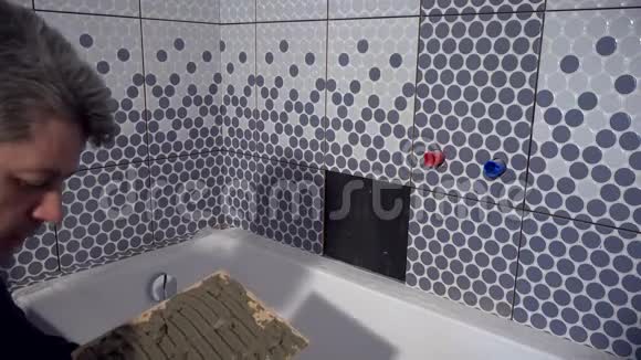 疲惫的工人安装最后一块瓷砖在浴室视频的预览图