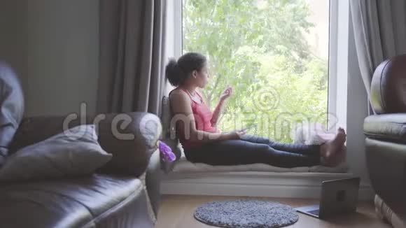 漂亮的非裔美国女人坐在窗台上用指甲锉剪指甲她关心自己视频的预览图