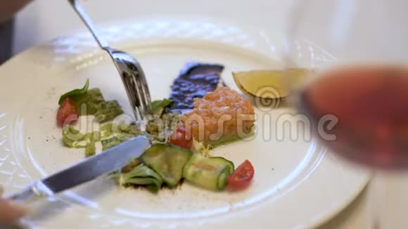 白色盘子有烤三文鱼和鳄梨馅饼加上新鲜的绿色沙拉女人用叉子和刀子轻轻地视频的预览图