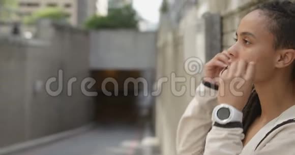 城市中戴耳机的年轻非洲裔美国妇女的侧视4k视频的预览图