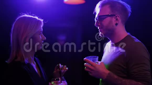 成人夫妇在酒吧喝鸡尾酒戴眼镜的男人和金发女人在迪斯科舞厅聊天在夜总会玩得开心视频的预览图